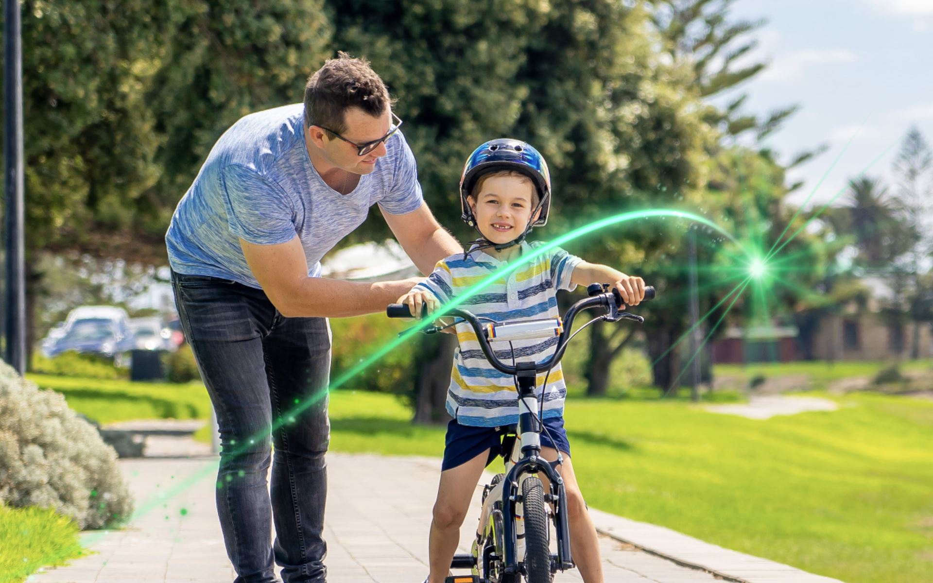 A father helping his son learn to ride a bike in a park
