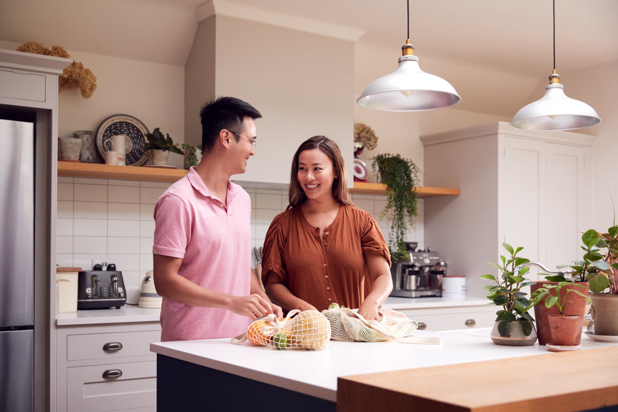 A couple unpacking groceries on their kitchen bench