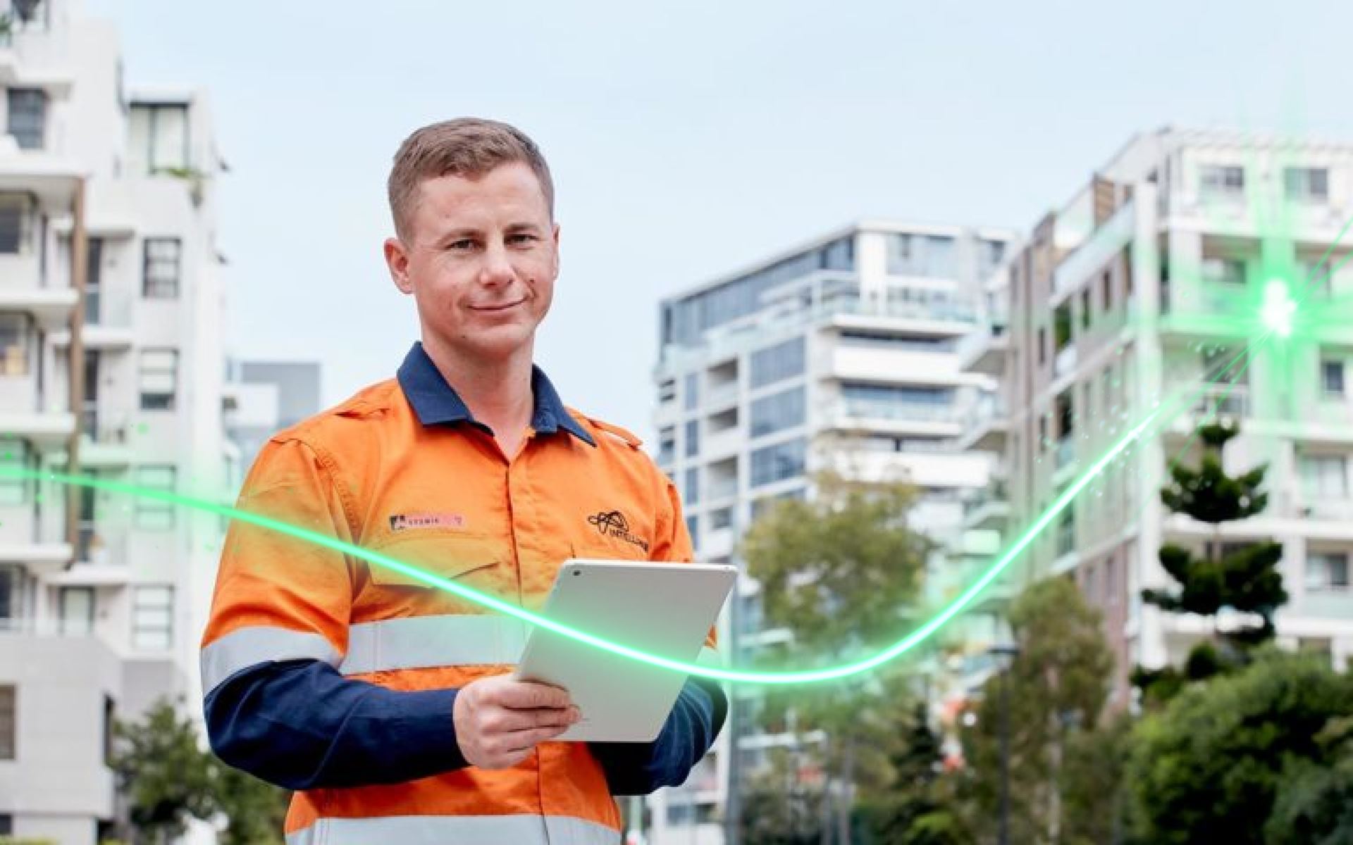 A man standing in middle of apartment buildings holding a tablet 