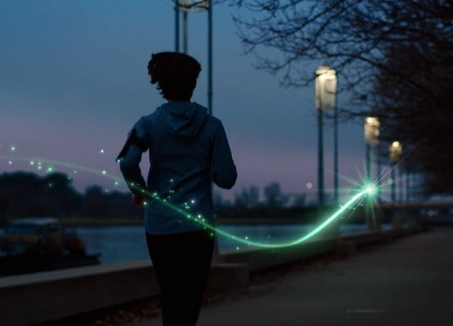 Silhouette of a person running on a path by a lake