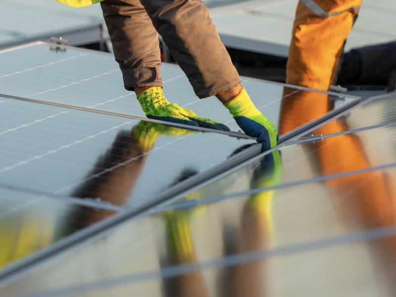 Solar panels being installed on a roof by a tradesman