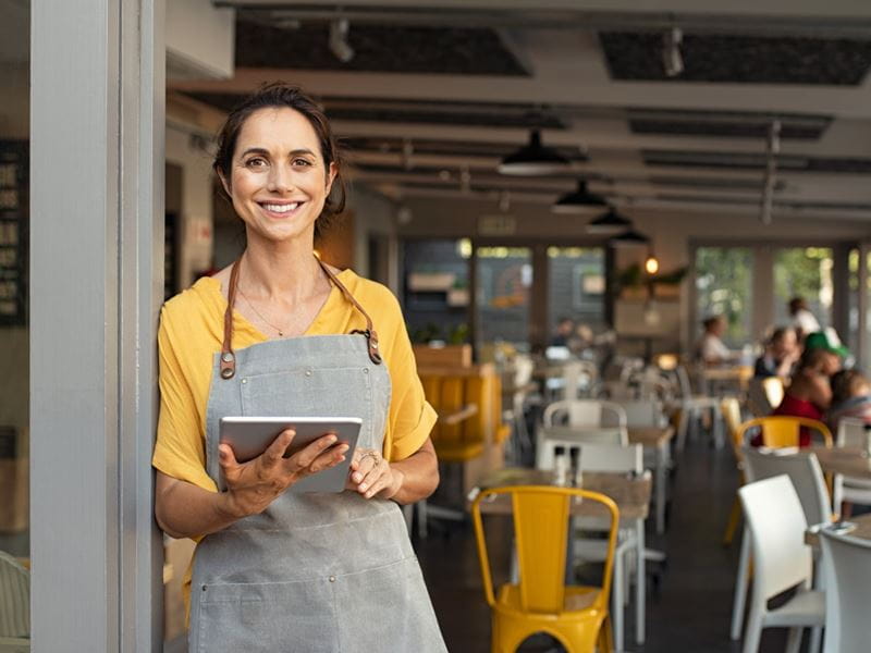 Cafe owner wearing an apron standing outside her business premises