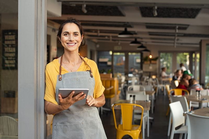 Local small business owner smiling and standing in front of her cafe