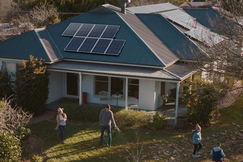A family playing in front of a solar powered house