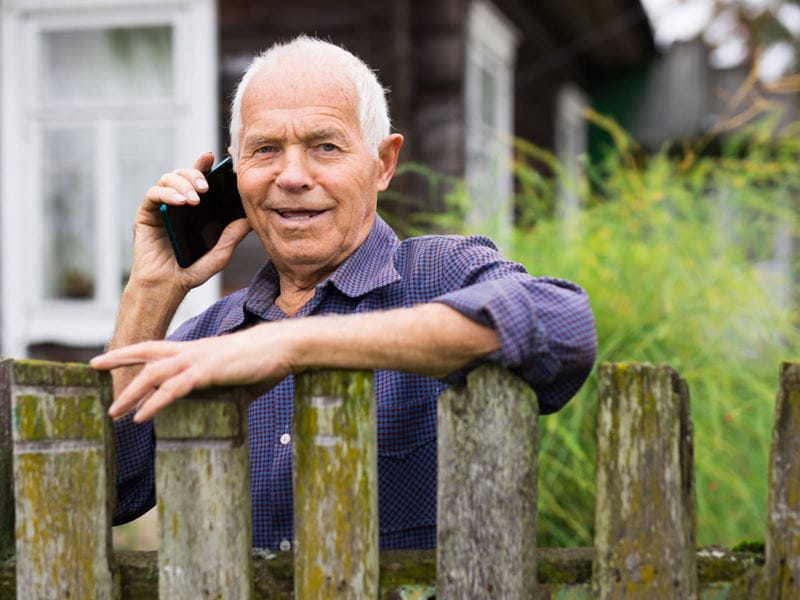 Man resting on a fence, engaged in a phone conversation
