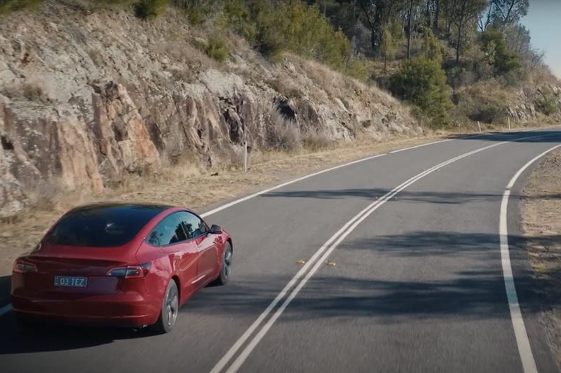 A Tesla electric vehicle cruising down the street
