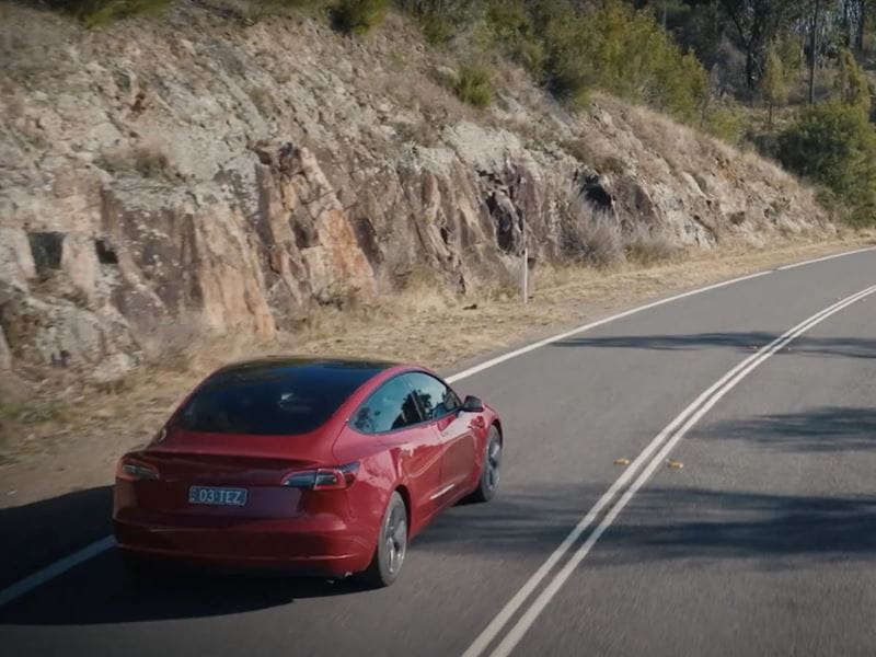 A red Tesla electric car driving on the road
