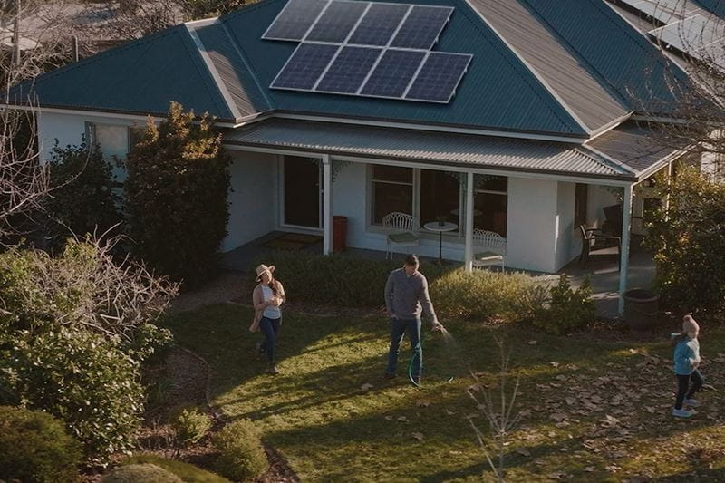 A couple outside their home, watering the garden together