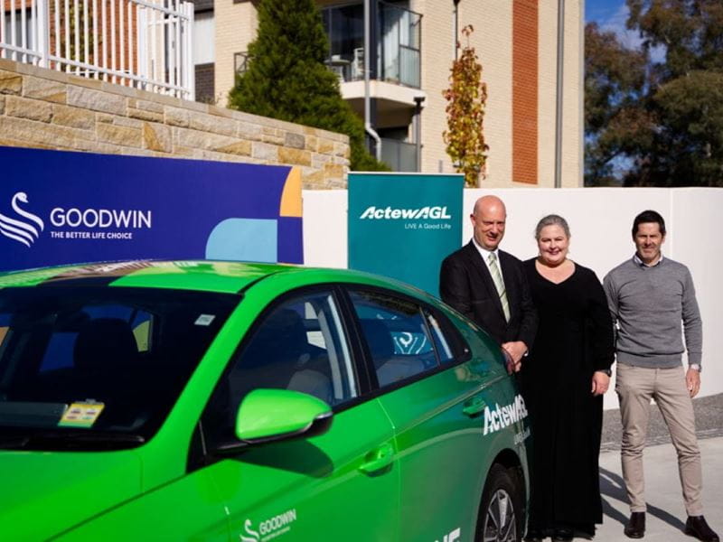 ActewAGL and Goodwin Aged Care Services management standing alongside an electric car