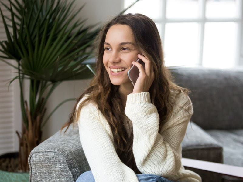 Woman sitting on a couch talking on a mobile phone 
