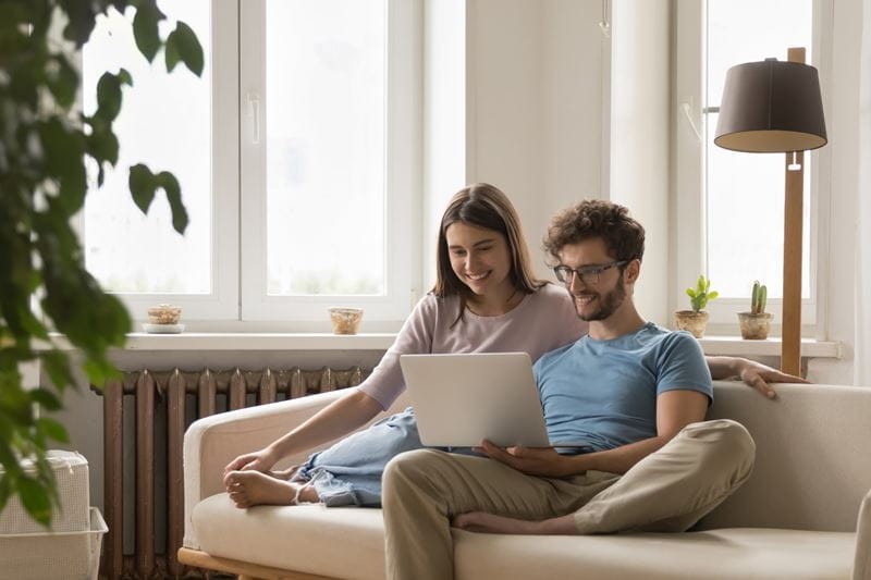 A man and woman sitting on the lounge with a laptop