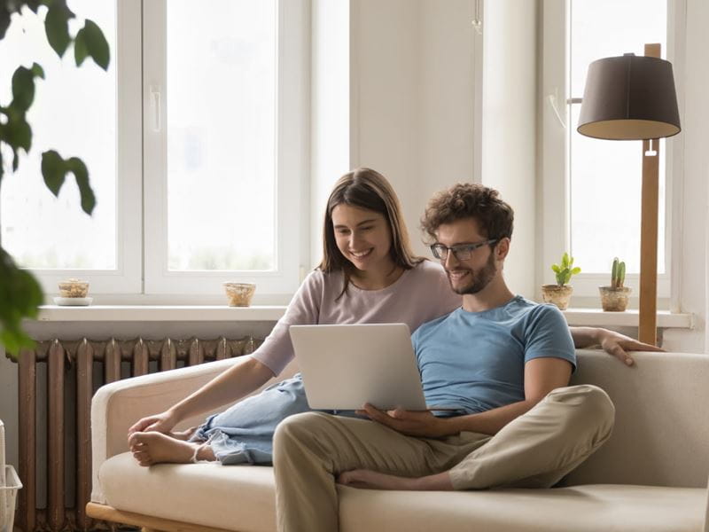 A couple sitting on the lounge with a laptop