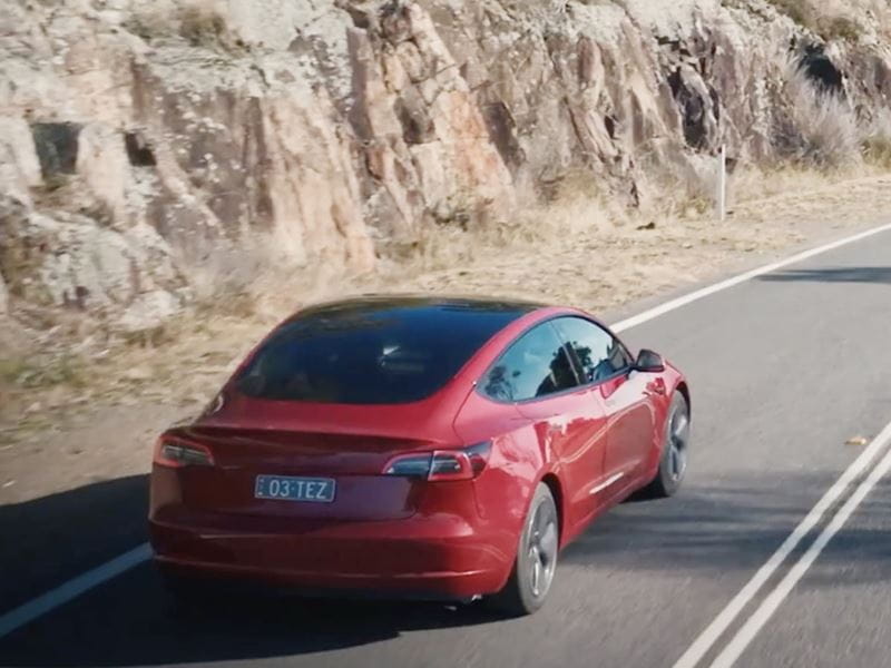 Red electric car travelling on a road