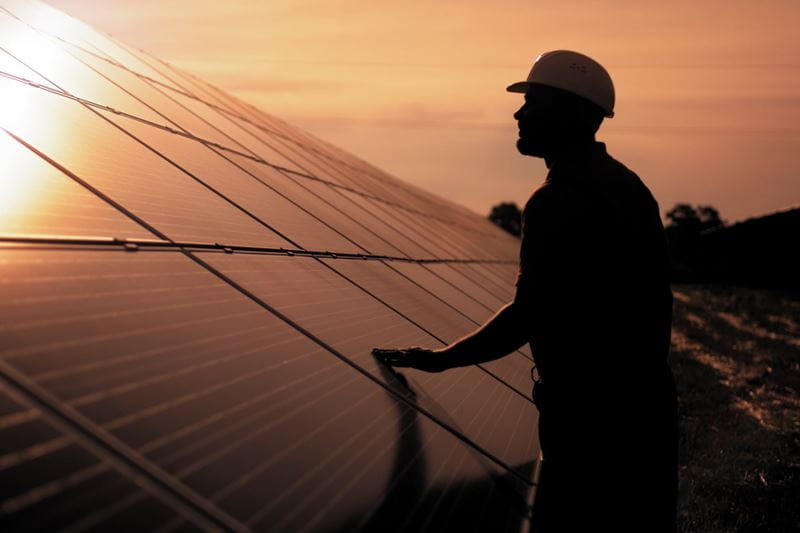 A man checking on solar panels during sunset