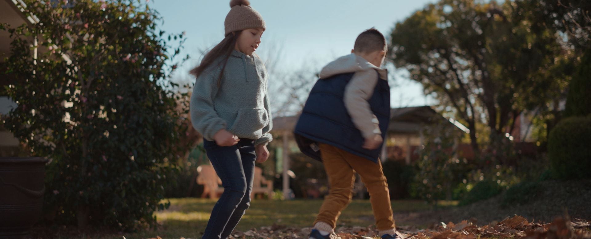A girl and a boy playing outside on a cool autumn day