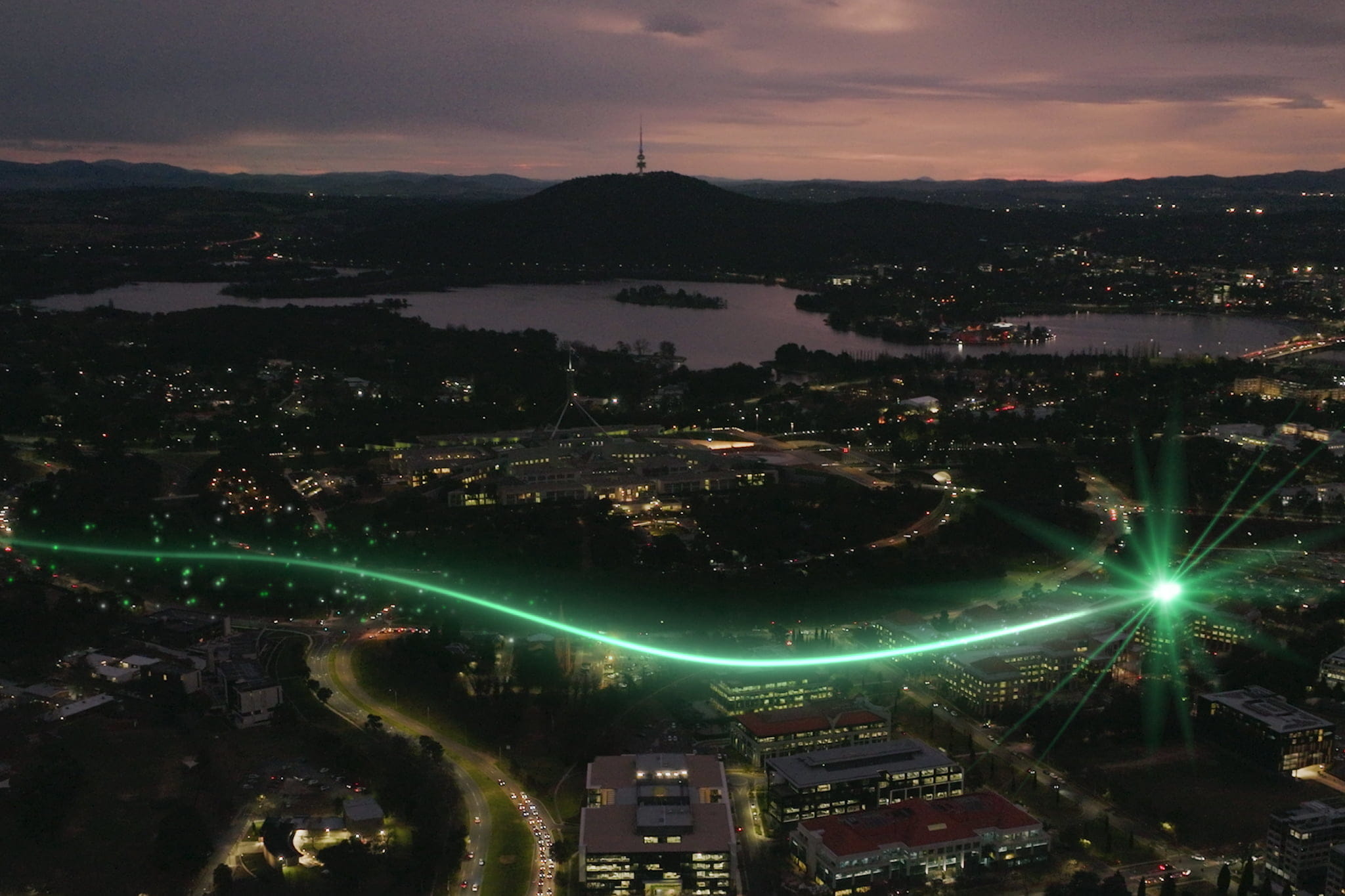 An aerial view portraying Canberra city at night with a green light