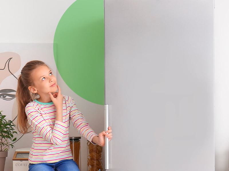 A girl sitting on a chair and looking at the refrigerator