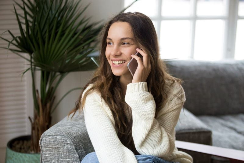Woman seated on a couch, talking on her mobile device